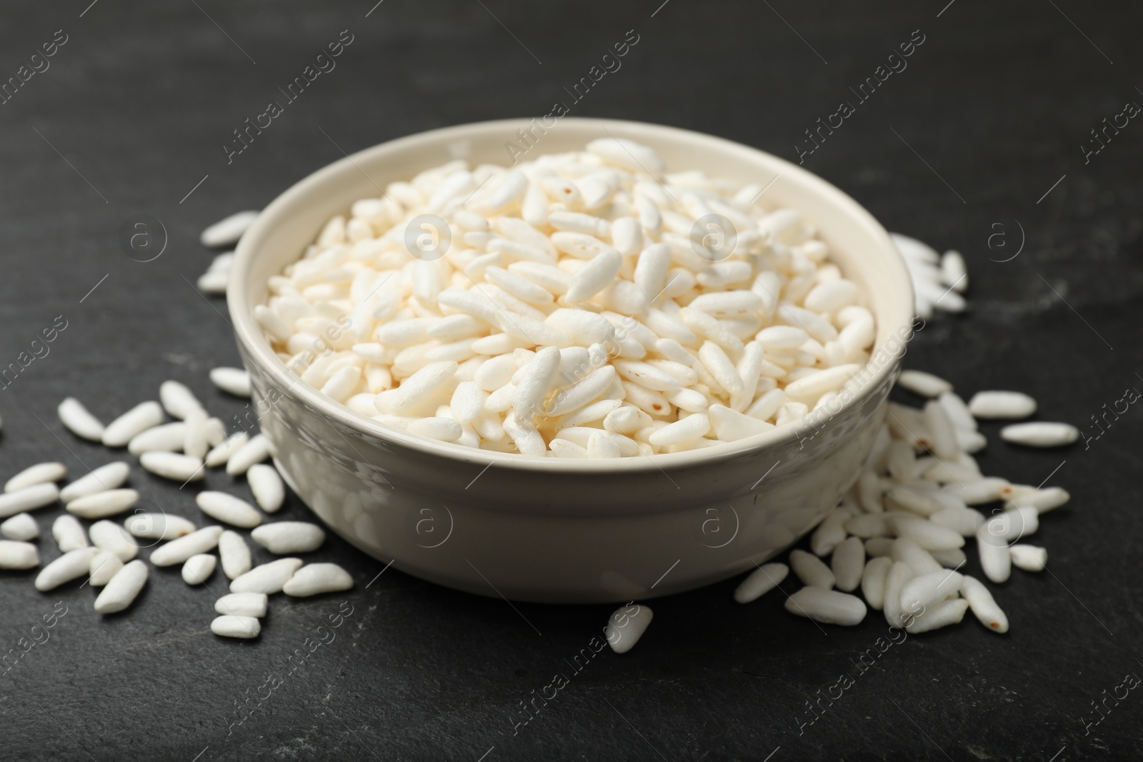 Photo of Puffed rice in bowl on dark table, closeup