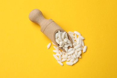 Photo of Scoop with puffed rice on yellow background, top view