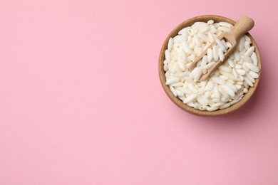 Photo of Puffed rice in bowl and scoop on light pink background, top view. Space for text