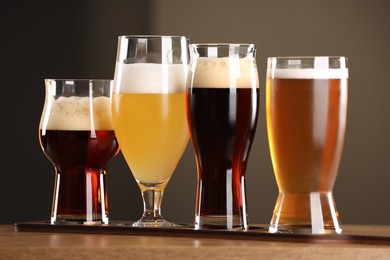 Photo of Glasses with different types of beer on wooden table indoors, closeup