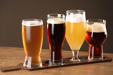 Photo of Glasses with different types of beer on wooden table indoors