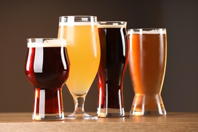 Photo of Glasses with different types of beer on wooden table indoors