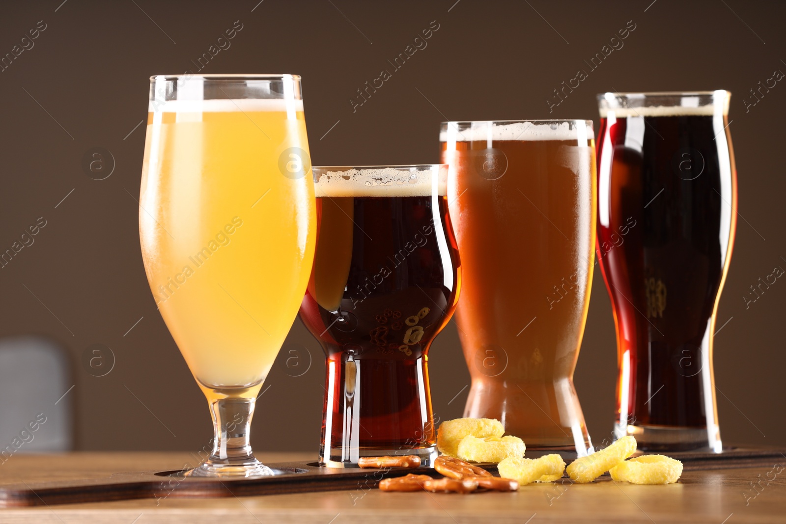 Photo of Glasses with different types of beer and snacks on wooden table indoors, closeup