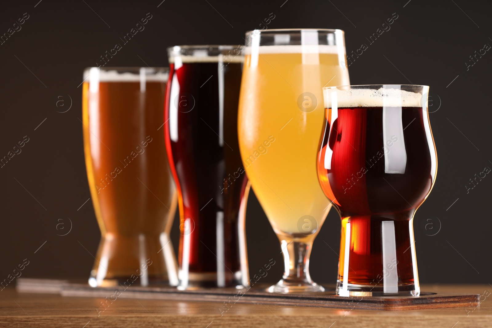 Photo of Glasses with different types of beer on wooden table indoors, closeup