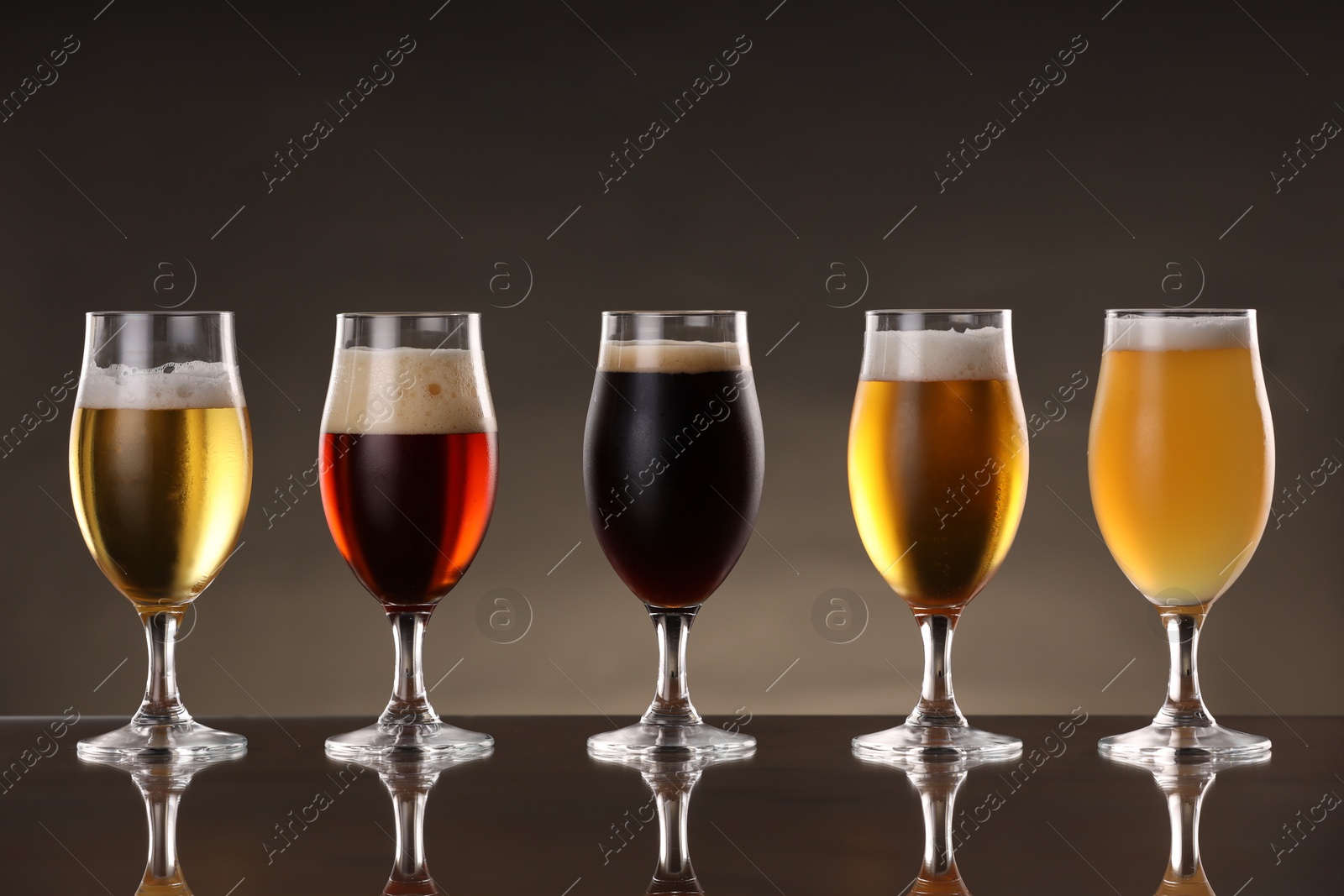 Photo of Glasses with different types of beer on mirror surface