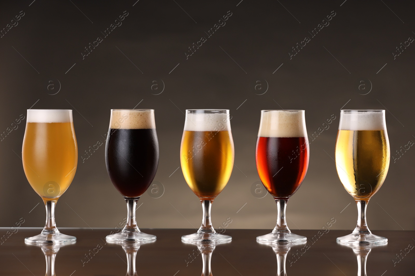 Photo of Glasses with different types of beer on mirror surface