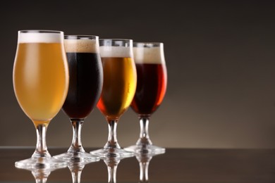 Photo of Glasses with different types of beer on mirror surface, closeup. Space for text