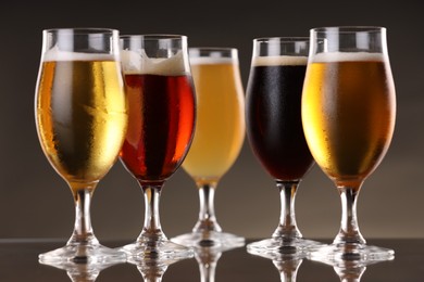 Photo of Glasses with different types of beer on mirror surface, closeup