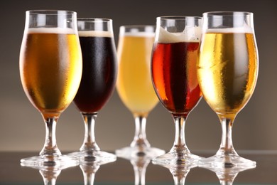 Photo of Glasses with different types of beer on mirror surface, closeup