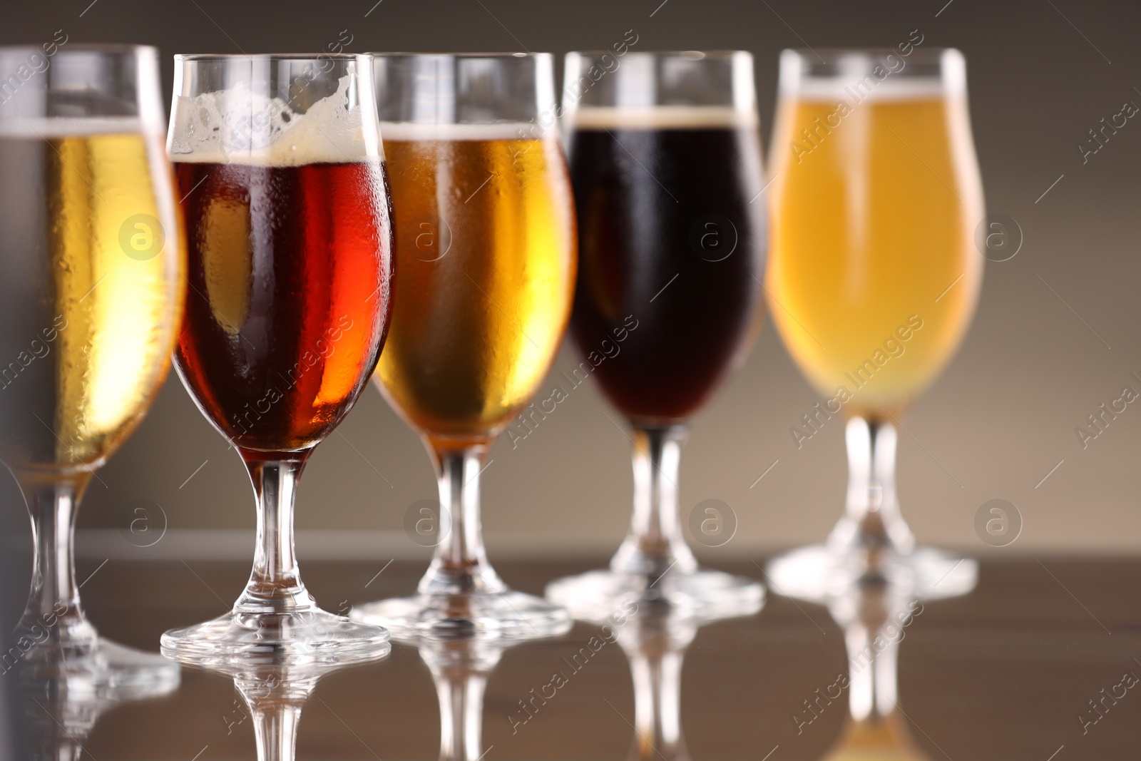 Photo of Glasses with different types of beer on mirror surface, closeup