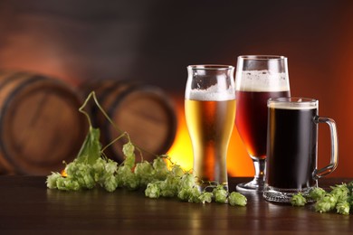 Photo of Glasses with different types of beer and fresh hops on wooden table in bar. Space for text