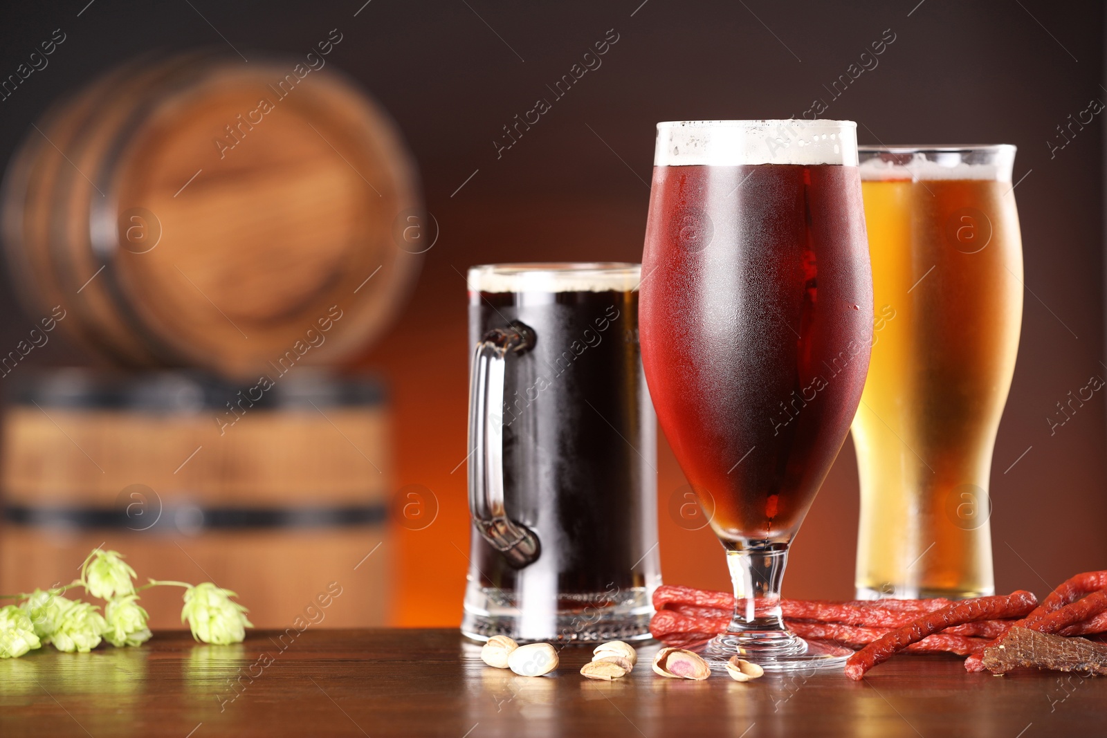 Photo of Glasses with different types of beer, snacks and fresh hops on wooden table in bar. Space for text