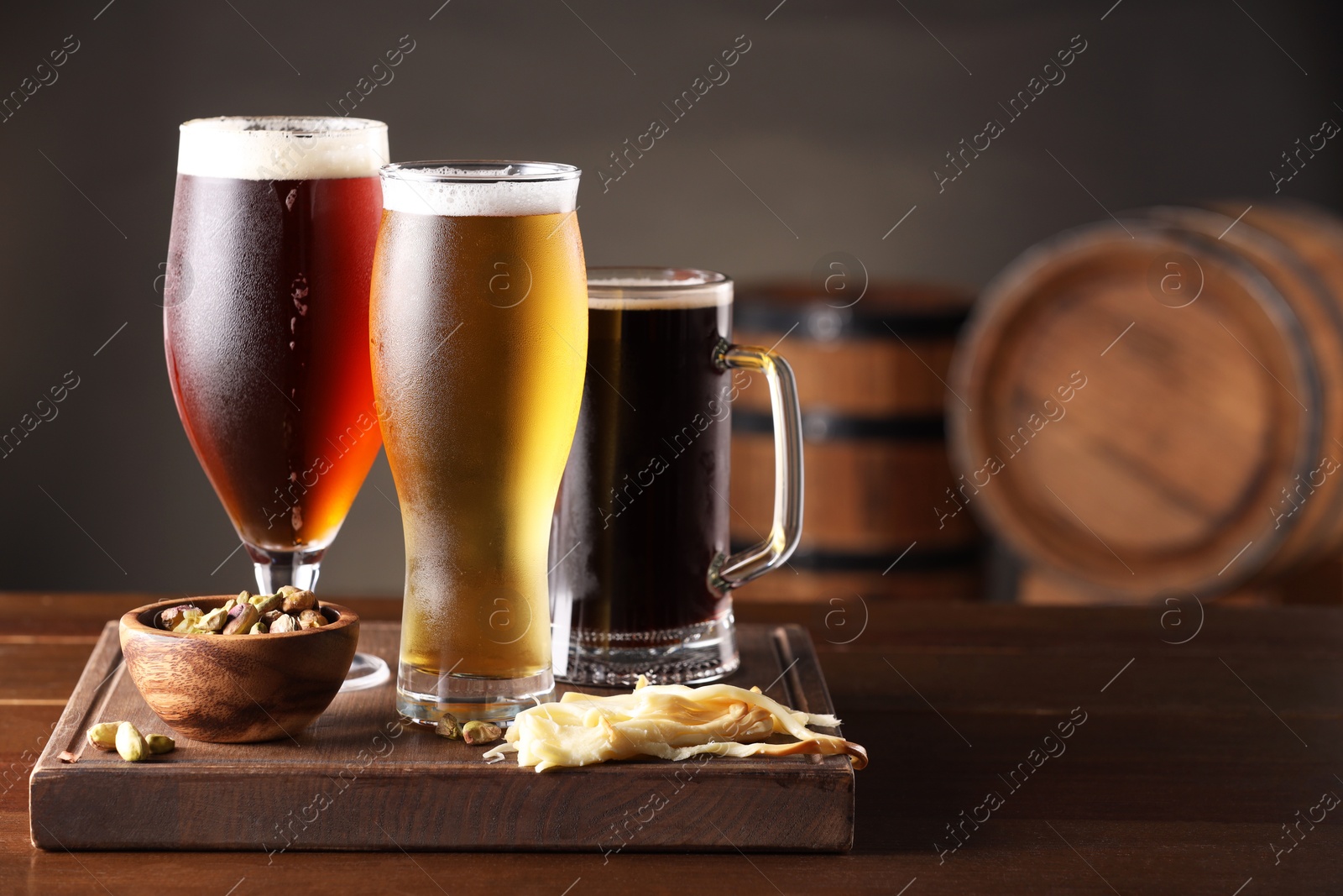 Photo of Glasses with different types of beer and snacks on wooden table in bar. Space for text