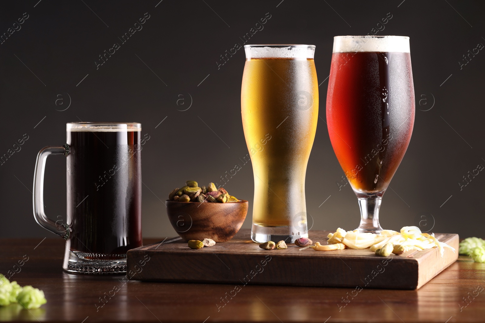 Photo of Glasses with different types of beer and snacks on wooden table