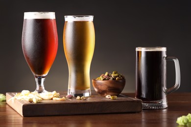 Photo of Glasses with different types of beer and snacks on wooden table