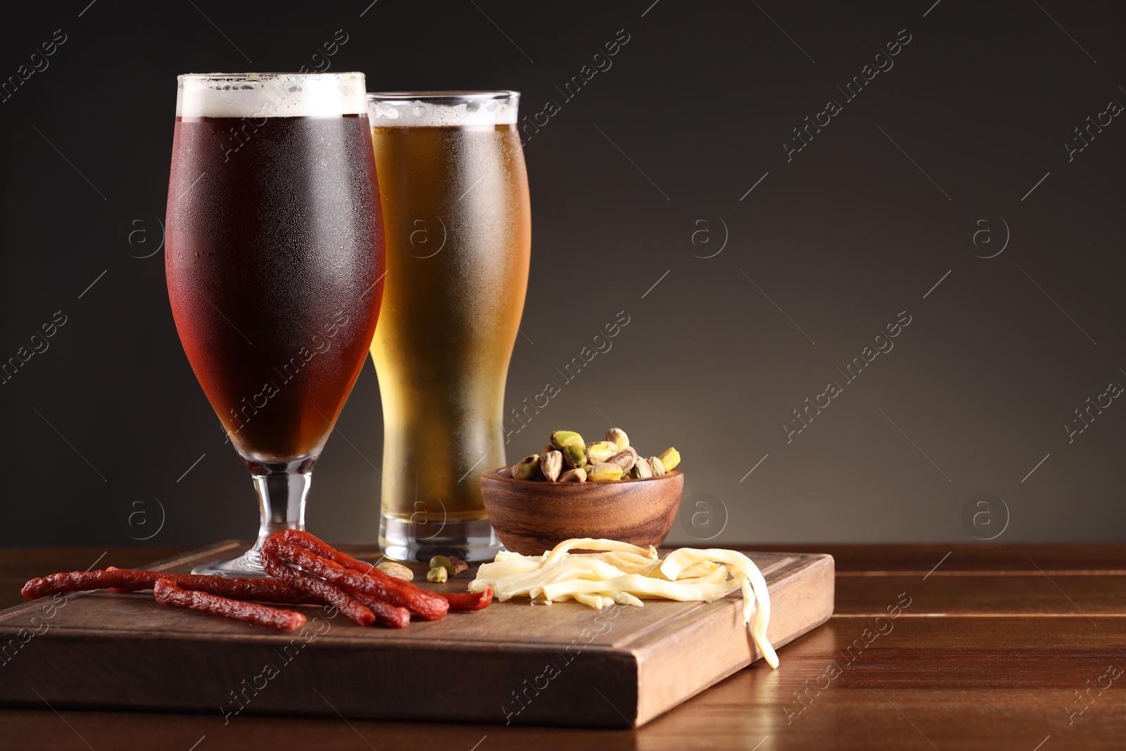 Photo of Glasses with different types of beer and snacks on wooden table. Space for text