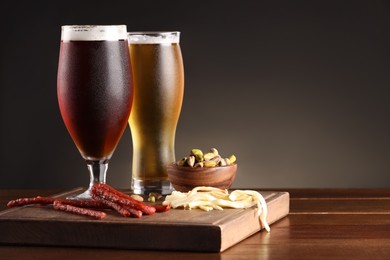 Photo of Glasses with different types of beer and snacks on wooden table. Space for text