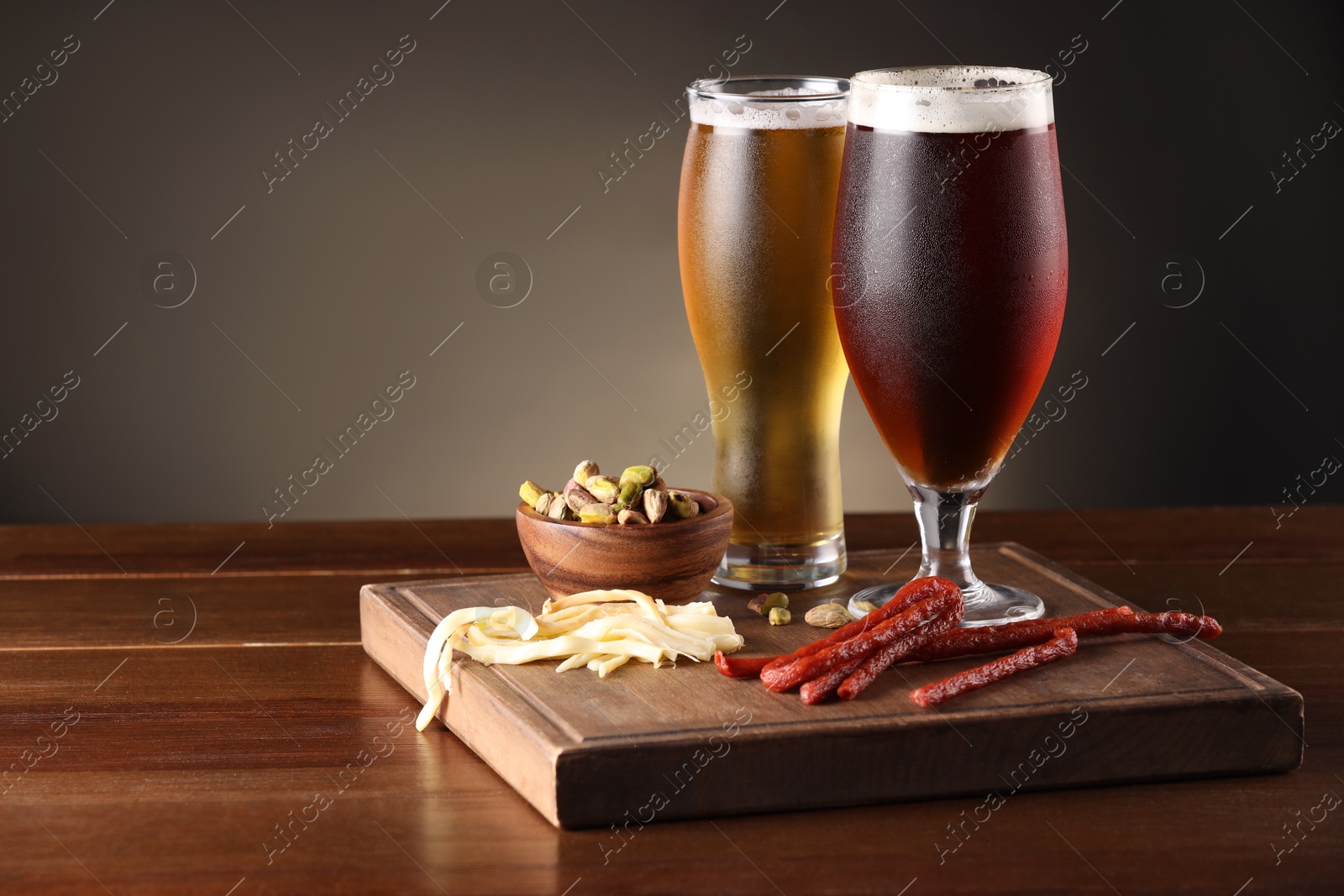 Photo of Glasses with different types of beer and snacks on wooden table. Space for text