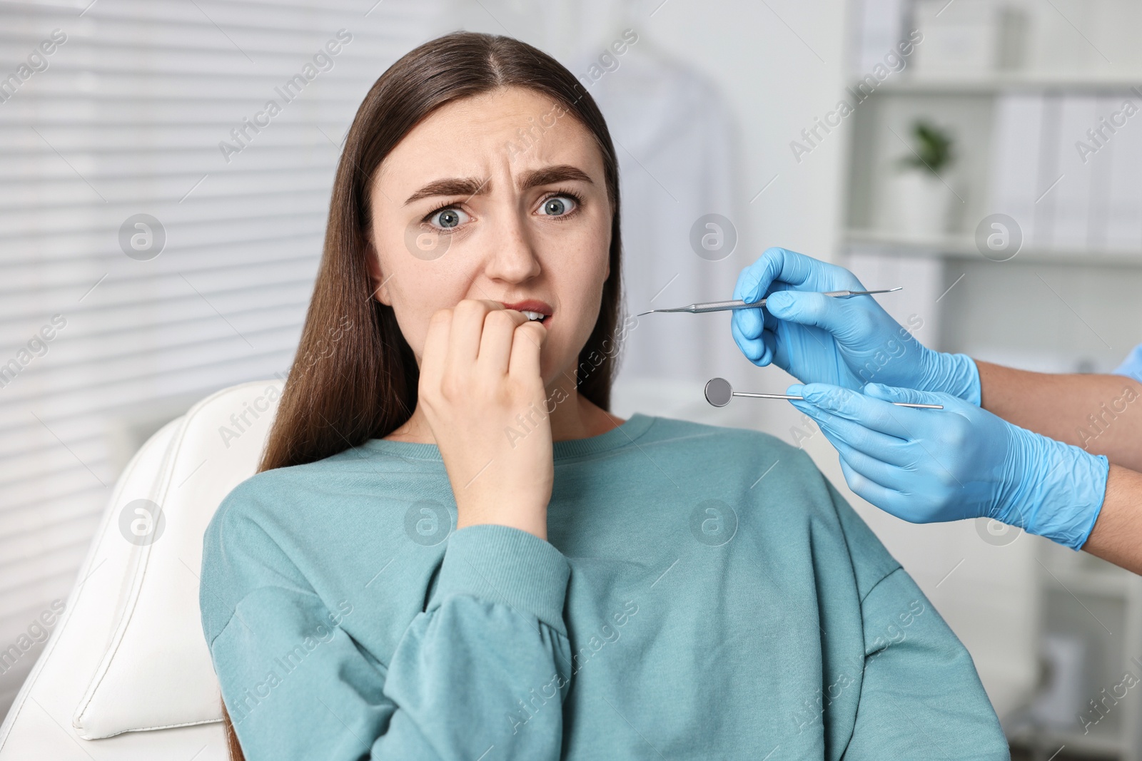 Photo of Dental phobia. Dentist working with scared woman in clinic, closeup