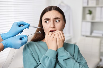 Dental phobia. Dentist working with scared woman in clinic, closeup