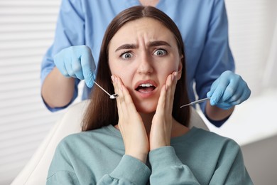 Dental phobia. Dentist working with scared woman in clinic, closeup