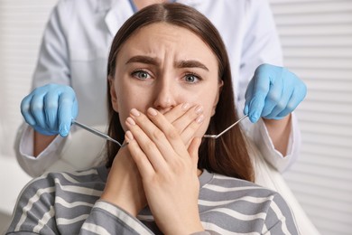 Dental phobia. Dentist working with scared woman in clinic, closeup