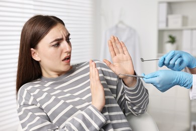 Photo of Dental phobia. Dentist working with scared woman in clinic, closeup