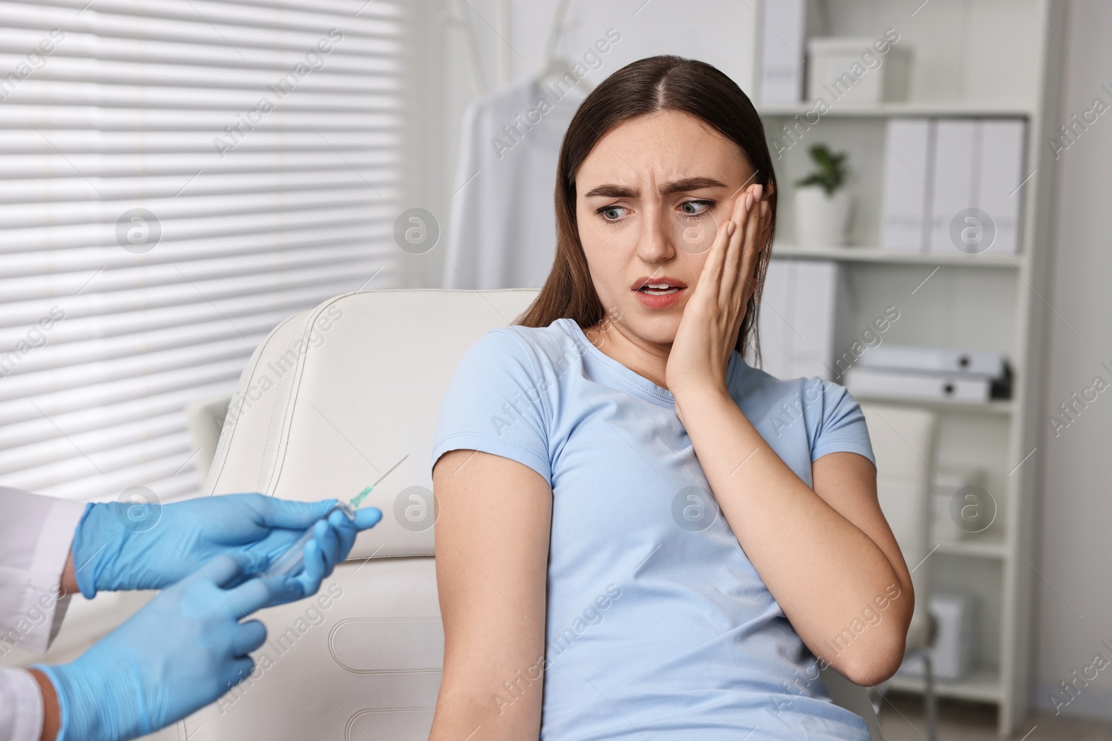 Photo of Dental phobia. Dentist with syringe near scared woman in clinic, closeup