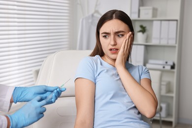 Dental phobia. Dentist with syringe near scared woman in clinic, closeup