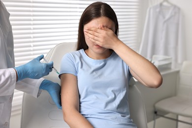 Photo of Dental phobia. Dentist with syringe near scared woman in clinic, closeup