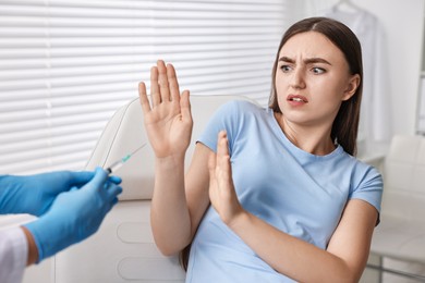 Dental phobia. Dentist with syringe near scared woman in clinic, closeup