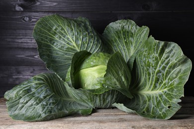 Photo of One ripe head of cabbage on wooden table, closeup