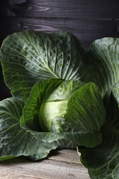 Photo of One ripe head of cabbage on wooden table, closeup