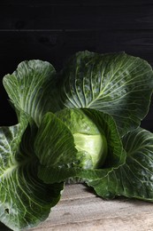 One ripe head of cabbage on wooden table