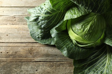 Photo of One ripe head of cabbage on wooden table, top view. Space for text