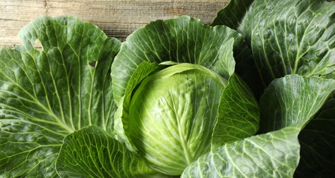 Photo of One ripe head of cabbage on wooden table, closeup