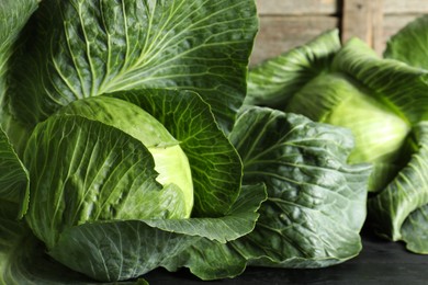 Ripe cabbages on black wooden table, closeup