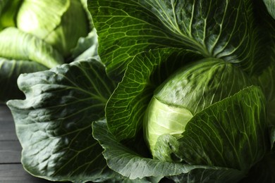 Photo of Ripe cabbages on black wooden table, closeup