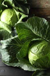 Photo of Ripe cabbages on black wooden table, closeup