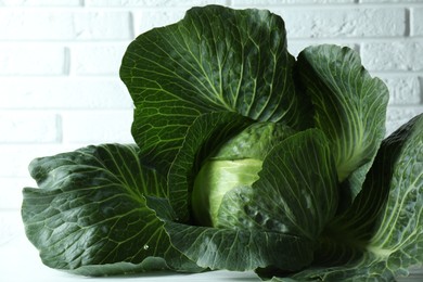 One ripe head of cabbage on white wooden table, closeup