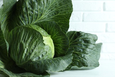 Photo of One ripe head of cabbage on white wooden table, closeup