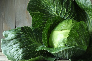 Photo of One ripe head of cabbage on wooden table, closeup