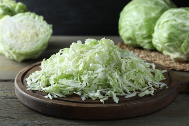 Photo of Fresh shredded cabbage on wooden table, closeup