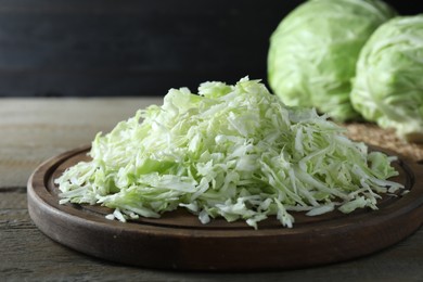 Photo of Fresh shredded cabbage on wooden table, closeup