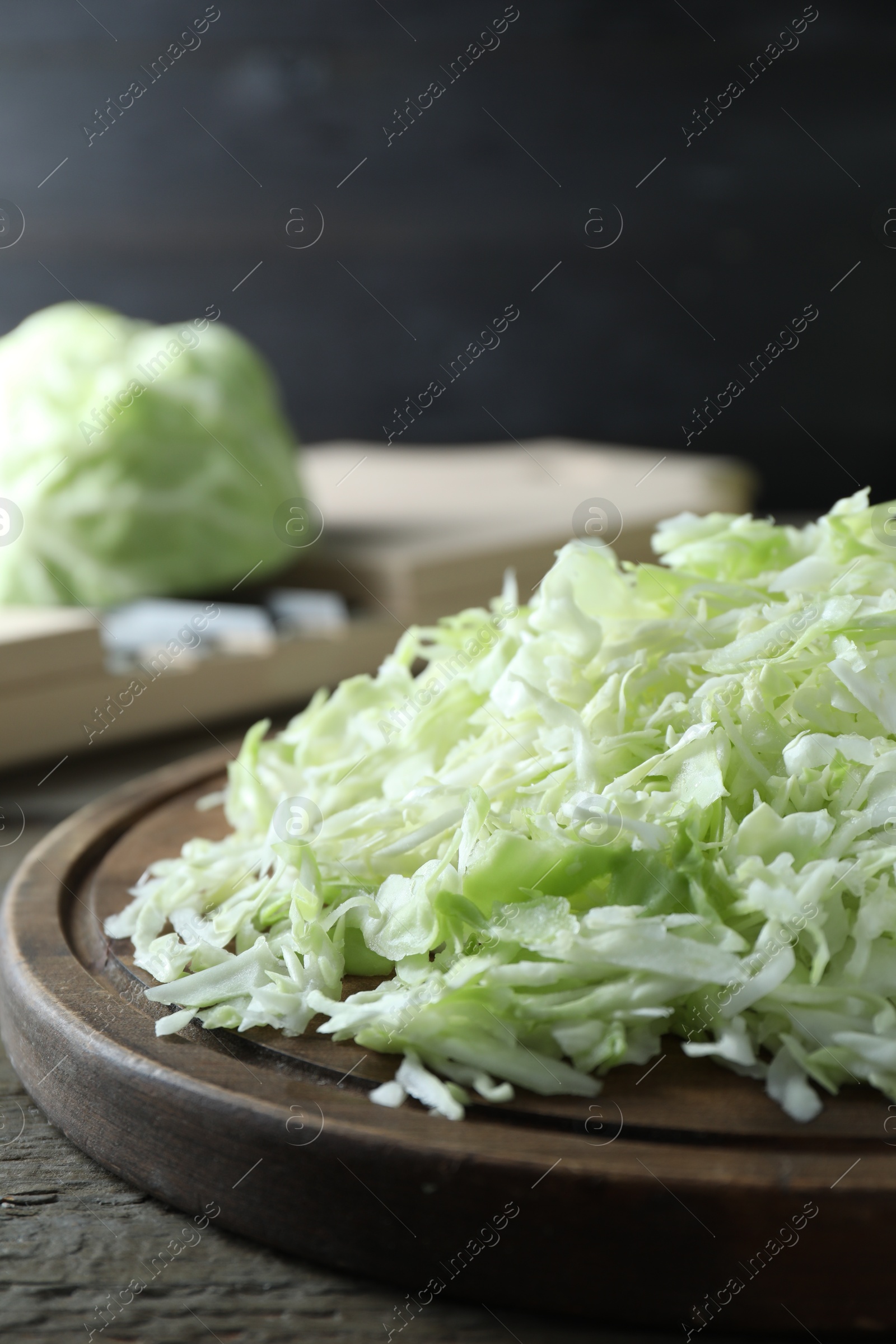 Photo of Fresh shredded cabbage on wooden table, closeup