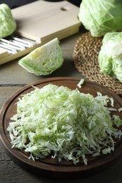 Photo of Fresh shredded cabbage on wooden table, closeup