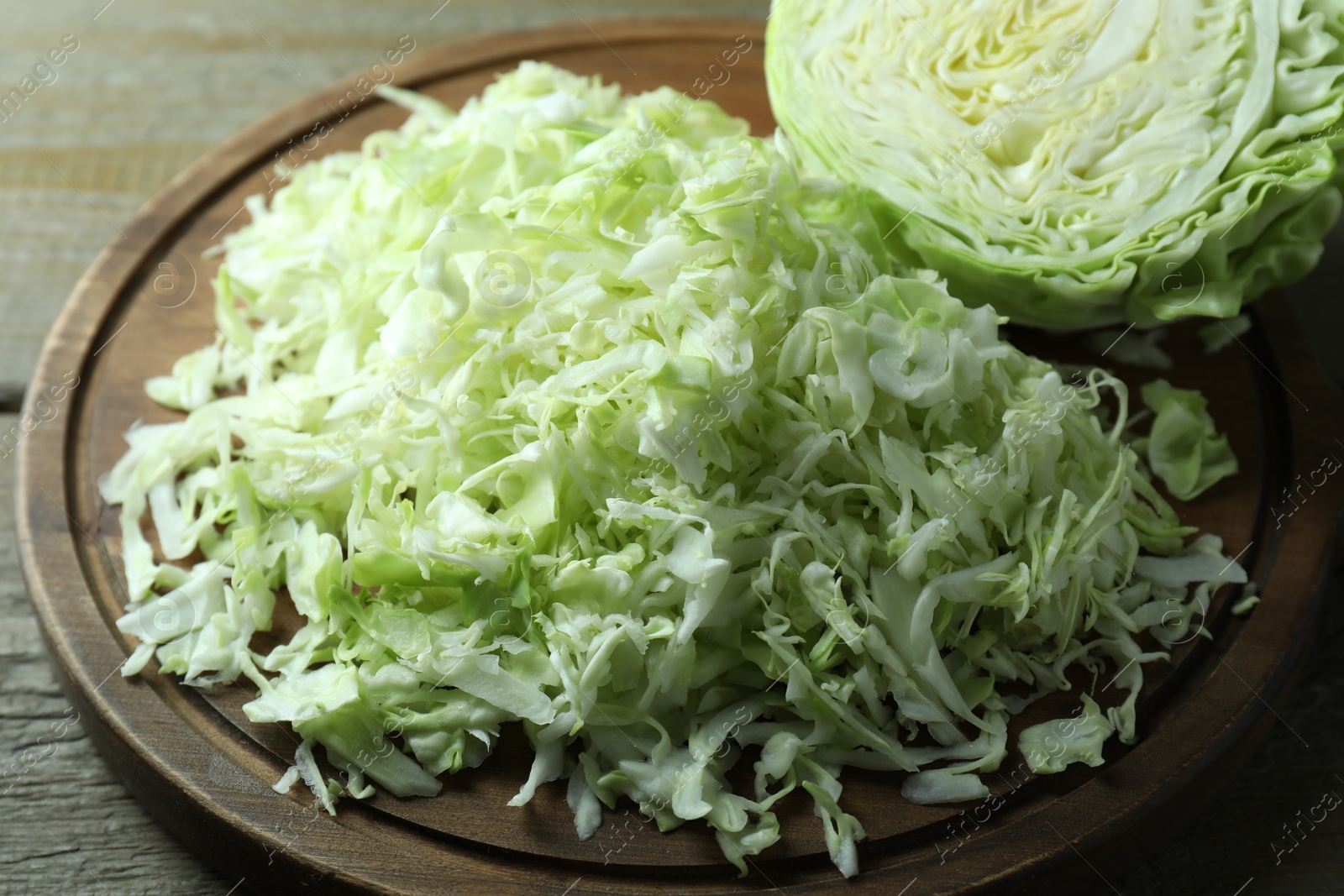 Photo of Fresh shredded cabbage on wooden table, closeup