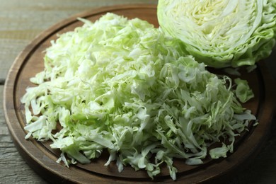 Photo of Fresh shredded cabbage on wooden table, closeup