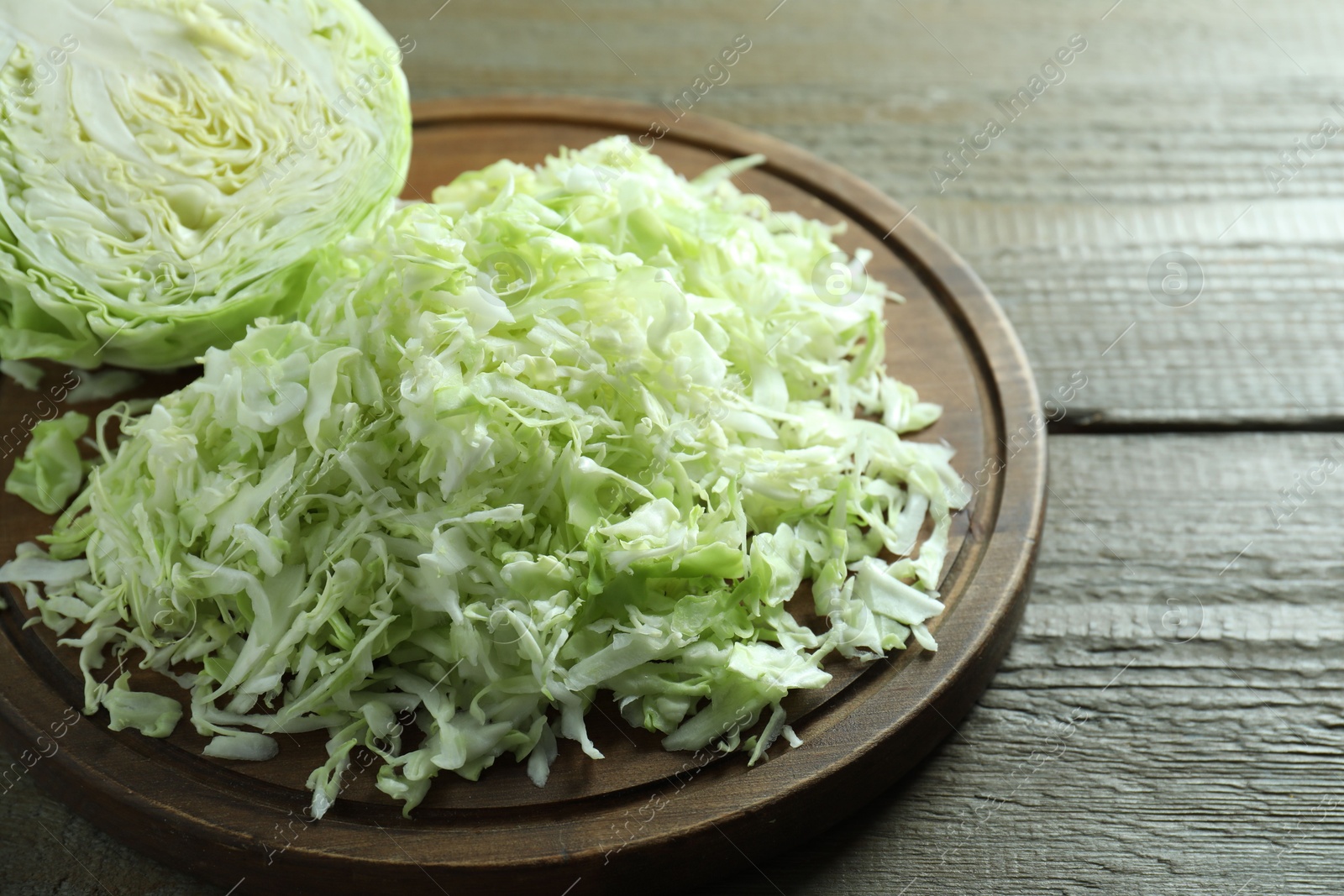 Photo of Fresh shredded cabbage on wooden table, closeup