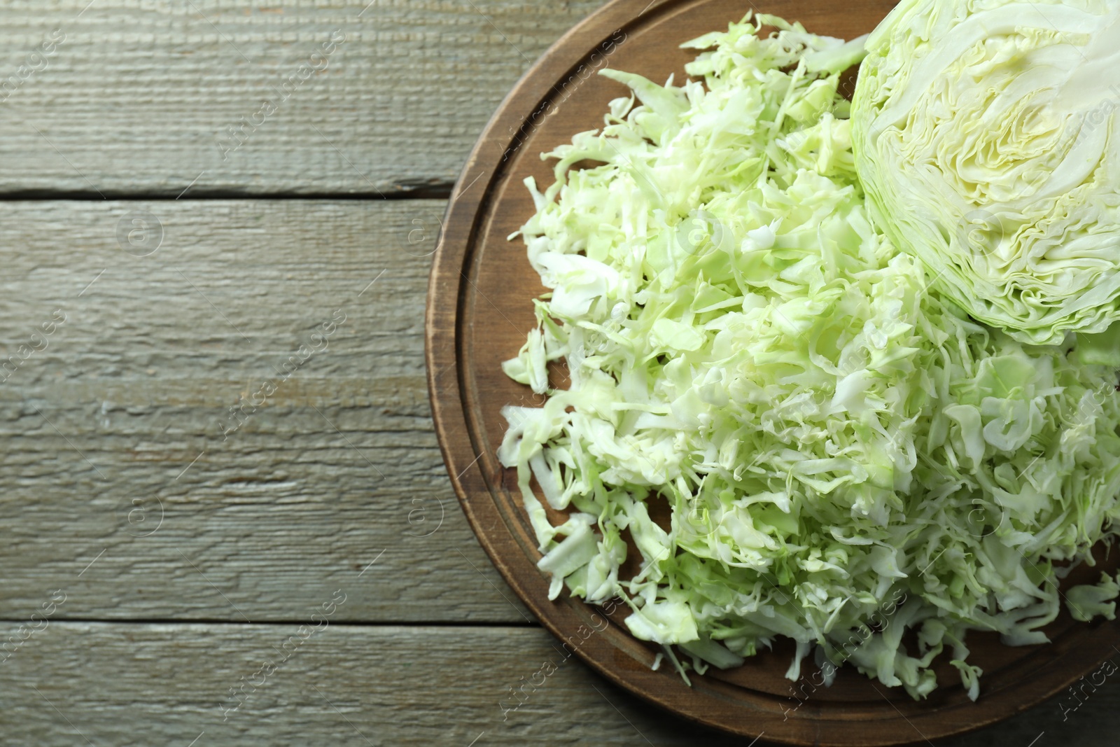 Photo of Fresh shredded cabbage on wooden table, top view. Space for text